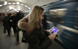 A young woman watches Vladimir Putin's annual press conference on a mobile device in a Moscow subway station. (file photo)