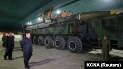 Солтүстік Корея басшысы Ким Чен Ын (сол жақта) әскерилермен бірге "Хвасон-14" құрлықаралық баллистикалық зымыранын қарап жүр. 5 шілде 2017 жыл.
