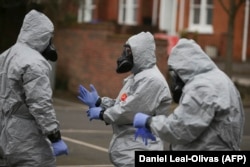 Military personnel wearing protective clothing work to remove vehicles from a cordoned-off area in Salisbury on March 11.