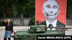 O tânără din ONG-ul „ARESEL” pozează lângă macheta unui tanc rusesc și un portret al lui Putin, 16 mai 2022. Zeci de activiști romi au protestat la Ambasada Rusiei din București față de o relatare a presei, că romii ucraineni ar fi furat un tanc rusesc.