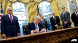 U.S. President Donald Trump signs an executive order alongside White House Chief of Staff Reince Priebus (center), U.S. Vice President Mike Pence (left), National Trade Council adviser Peter Navarro (3rd right), senior adviser Jared Kushner (2nd right) and senior policy adviser Stephen Miller in the Oval Office of the White House in Washington, D.C., on January 23.