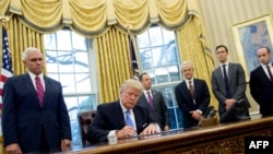 Момент подписания указа президентом США Дональдом Трампом в Овальном кабинете в Белом доме. Вашингтон, 23 января 2017 года.