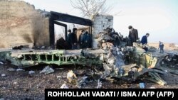 People stand near the wreckage after a Ukrainian plane carrying 176 passengers crashed near Imam Khomeini airport in Tehran on January 8, 2020.