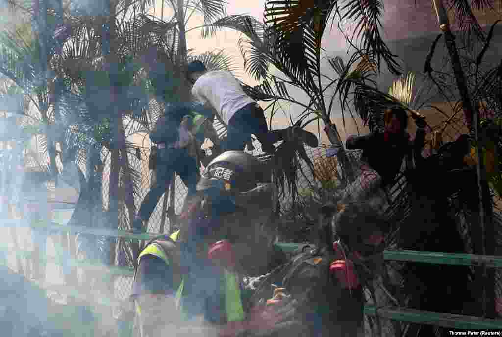 Protesters run from tear gas as they try to reenter the campus of Hong Kong Polytechnic University (PolyU) after a failed attempt to leave, during clashes with police in Hong Kong on November 18. (Reuters/Thomas Peter)&nbsp;