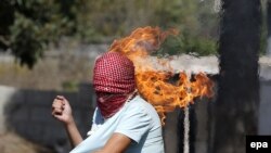Fələstinli gənc İsrail əsgərlərinə etiraz edərkən (Reuters)