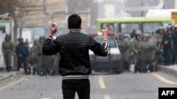 An Iranian opposition protester holds stones as he stands opposite security forces during clashes in Tehran on December 27, 2009.