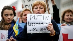 Жена държи в ръце надпис "Путин - терорист № 1 в света" по време на протестен митинг срещу анексията на Крим пред централата на ЕС в Брюксел, 17 март 2014 г.