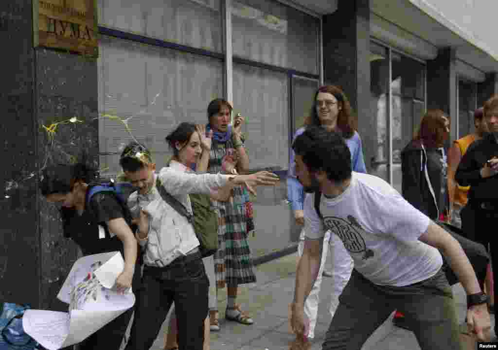 An Orthodox believer throws an egg at gay-rights activists outside the State Duma.