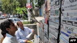 Pakistanis in Islamabad read newspapers the day after Pervez Musharraf's resignation on August 18, 2008.