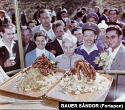 Приехавшие на фестиваль в западной Венгрии в 1959 году любуются горами колбасы