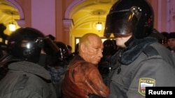 Police detain a man wearing a Vladimir Putin mask during an opposition protest in St. Petersburg.