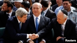 Госсекретарь США Джон Керри пожимает руку президенту Израиля Шимону Пересу во время траурной церемонии памяти жертв Холокоста. В центре - премьер Израиля Биньямин Нетаньяху