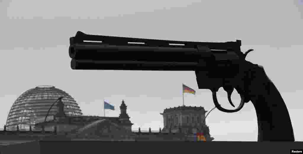 A sculpture showing a pistol, inspired by Swedish artist Carl Frederik Reutersvaerd&#39;s sculpture &quot;Non-Violence,&quot; is pictured in front of the Reichstag in Berlin. A German peace initiative used the sculpture to protest against the German arms trade. (Reuters/Fabrizio Bensch)
