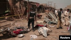 Pakistani police and security officials collect evidence at the site of a bomb blast in Dera Allah Yar, in Balochistan Province, on March 22.