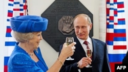 Dutch Queen Beatrix and Russian President Vladimir Putin raise their glasses after they unveiled a plaque during their visit to the Hermitage Museum in Amsterdam on April 8.