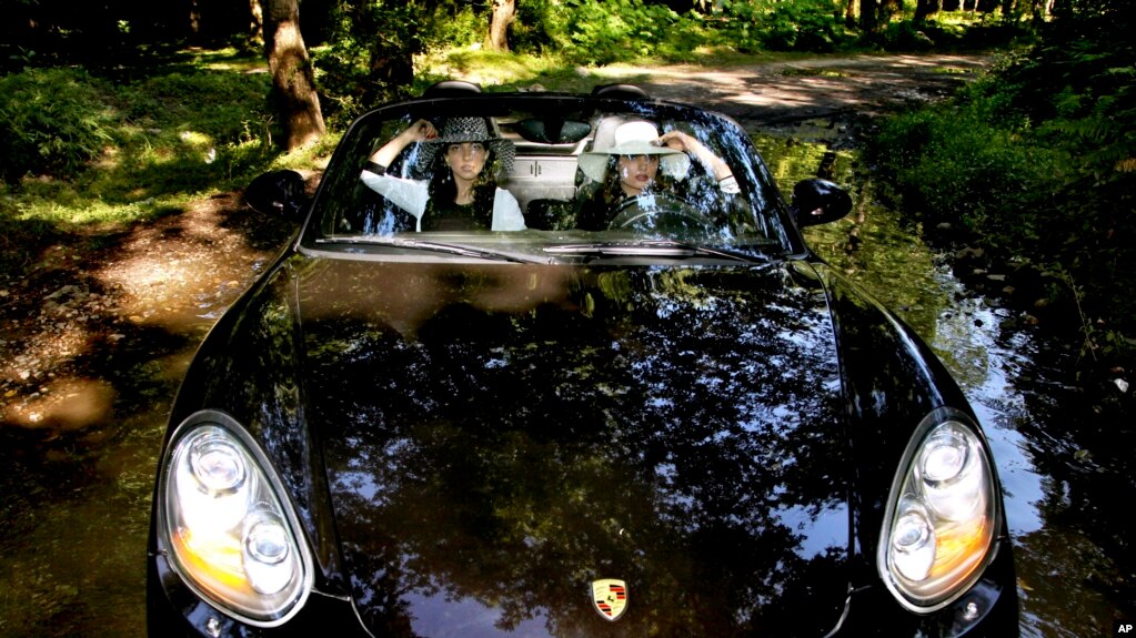 In this picture taken on Friday, May 24, 2013, two Iranian women ride in a Porsche, in Noor forest, northern Iran. (AP Photo/Ebrahim Noroozi)