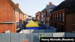 A British police officer on July 5 stands in front of screening erected in Amesbury, Britain, as forensic tents are erected after officials said it was confirmed that two people were poisoned with the nerve agent Novichok.