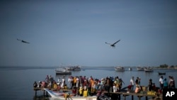 In this Sept. 13, 2016 photo, people gather on a pier to buy sardines from fishermen in the Los Cocos area of Porlamar, Margarita Island, Venezuela. Some are buying for their own consumption, and others to resell. (AP Photo/Ariana Cubillos)