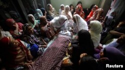 Mourners sit around the body of a boy who was killed in a bomb blast in Karachi in August.