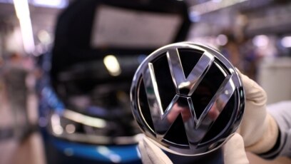 Zaposlenik drži Volkswagen logo u proizvodnoj liniji u fabrici Volkswagena u Wolfsburgu, Njemačka, 1. marta 2019.
