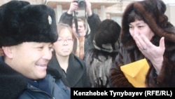 Полиция офицері оппозиция белсендісі Маржан Аспандияроваға (оң жақта) сотқа шақыру қағазын тапсырды. Алматы, 30 қаңтар 2012 жыл.