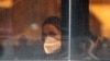 An Iranian woman wearing face mask sits in a bus in Tehran, February 26, 2020