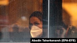 An Iranian woman wearing face mask sits in a bus in Tehran, February 26, 2020