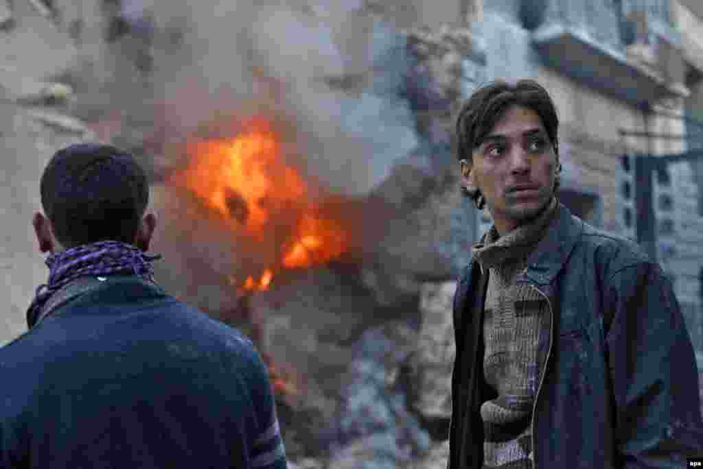 Syrian civilians look on as a building erupts in flames after a government air strike in Aleppo on February 26. (epa/Ali Mustafa)