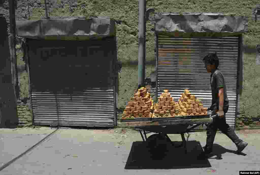 A young Afghan young boy carries traditional sweets with a handcart to a market ahead of the upcoming Eid al-Fitr holiday, marking the end of the holy fasting month of Ramadan in the old part of Kabul on June 13. (AP/Rahmat Gul)
