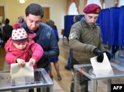 People cast their ballot at a polling station in Kyiv earlier today.