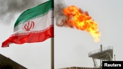 FILE PHOTO: A gas flare on an oil production platform in the Soroush oil fields is seen alongside an Iranian flag