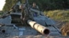 Ukrainian soldiers sit atop a tank that's dug in at a position outside Luhansk on June 29.