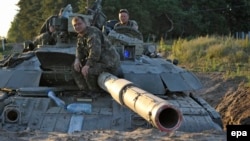 Ukrainian soldiers sit atop a tank that's dug in at a position outside Luhansk on June 29.