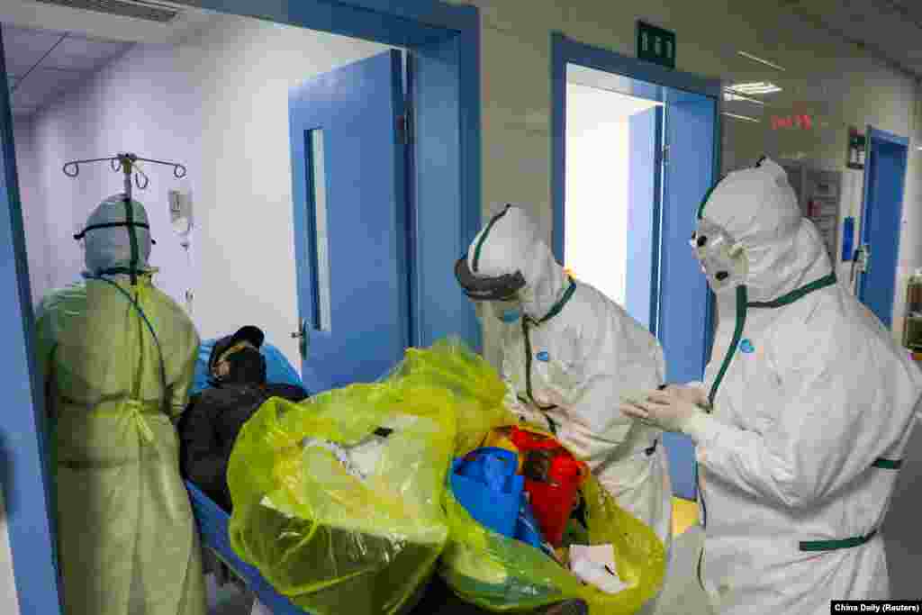 Медики в защитных костюмах перевозят больного коронавирусом в изолированную палату больницы в китайском городе Ухань.