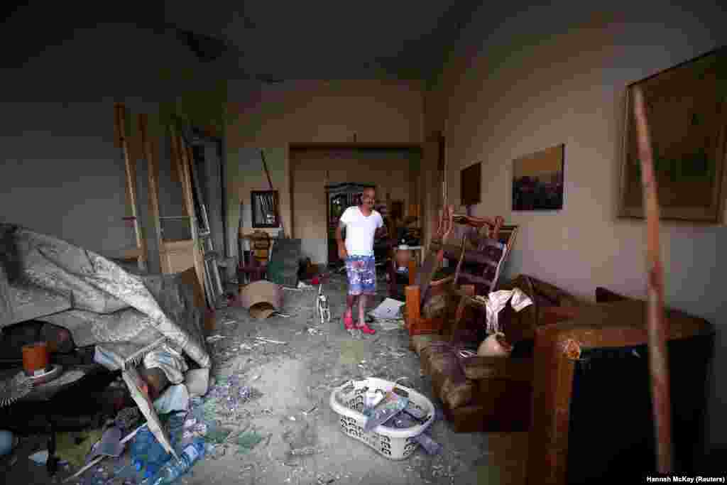 Michel Assad and his dog Pepsi stand inside their home that was damaged in Tuesday's blast in Beirut's port area, Lebanon, August 7, 2020. 