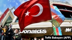 People wave the Turkish (center) national flag and the Azerbaijani flag as they celebrate victory in the streets of Baku on November 10.