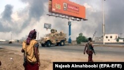 YEMEN -- Yemeni government forces patrol as smoke billows from an alleged Houthi position during battles between Yemeni government forces and Houthi rebels in the port city of Hodeidah, September 12, 2018.