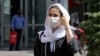 IRAN PANDEMIC CORONAVIRUS COVID19 -- Iranians wearing face masks walk past in a street of Tehran, Iran, 04 August 2020. 