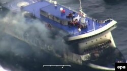  قوای ساحلی ایتالیا در حال کمک به افراد گیرمانده در داخل کشتی هستتد که آتش گرفته است