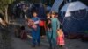 Internally displaced Afghans who fled from Kunduz, Takhar, and Baghlan provinces due to battles between the Taliban and Afghan security forces walk past temporary tents at the Sara-e Shamali camp in Kabul on August 11.
