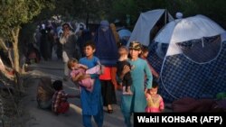 Familiile afgane strămutate intern, care au fugit din provinciile Kunduz, Takhar și Baghlan din cauza luptelor dintre talibani și forțele de securitate afgane, trec pe lângă corturile lor temporare amplasate în Sara-e-Shamali, Kabul, 11 august 2021.