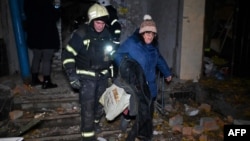 Ukrainian rescue workers evacuate a local resident from a multistory building that was damaged in a Russian air strike on Kharkiv on November 8.