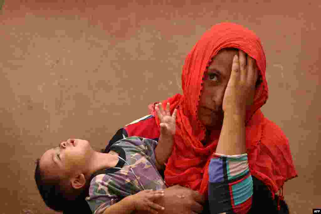 An Iraqi woman and her child, who fled the violence around the northern Iraqi city of Mosul, rest in the Dibaga camp in the town of Makhmur before returning to their village south of Mosul. (AFP/Safin Hamed)