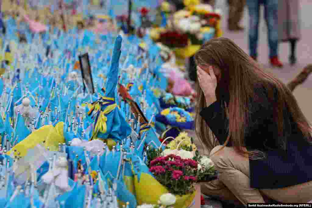 Жінка плаче біля народного меморіалу з прапорців на честь загиблих оборонців Україні на Майдані Незалежності у Києві. 1 жовтня 2024 року