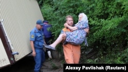 Рятувальник несе пенсіонерку на місці підтоплення в Куйбишевому, Бахчисарайський район