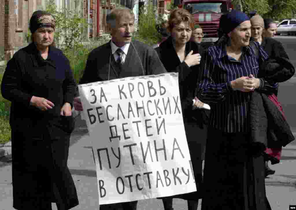Beslan relatives demonstrate outside the Kulayev trial in May 2006, holding anti-Putin placards (epa) - Survivors are not alone in distrusting authorities over Beslan. A poll published last week by Russia's Levada Center found that only 8 percent of respondents believe the government has told the whole truth.