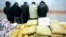 A pile of drugs is displayed in front of a group of suspected drug traffickers arrested in Iran.
