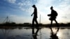 Dy njerëz duke ecur mbi një pellg uji në një rrugë në Afrikën e Jugut, më 26 maj 2023.