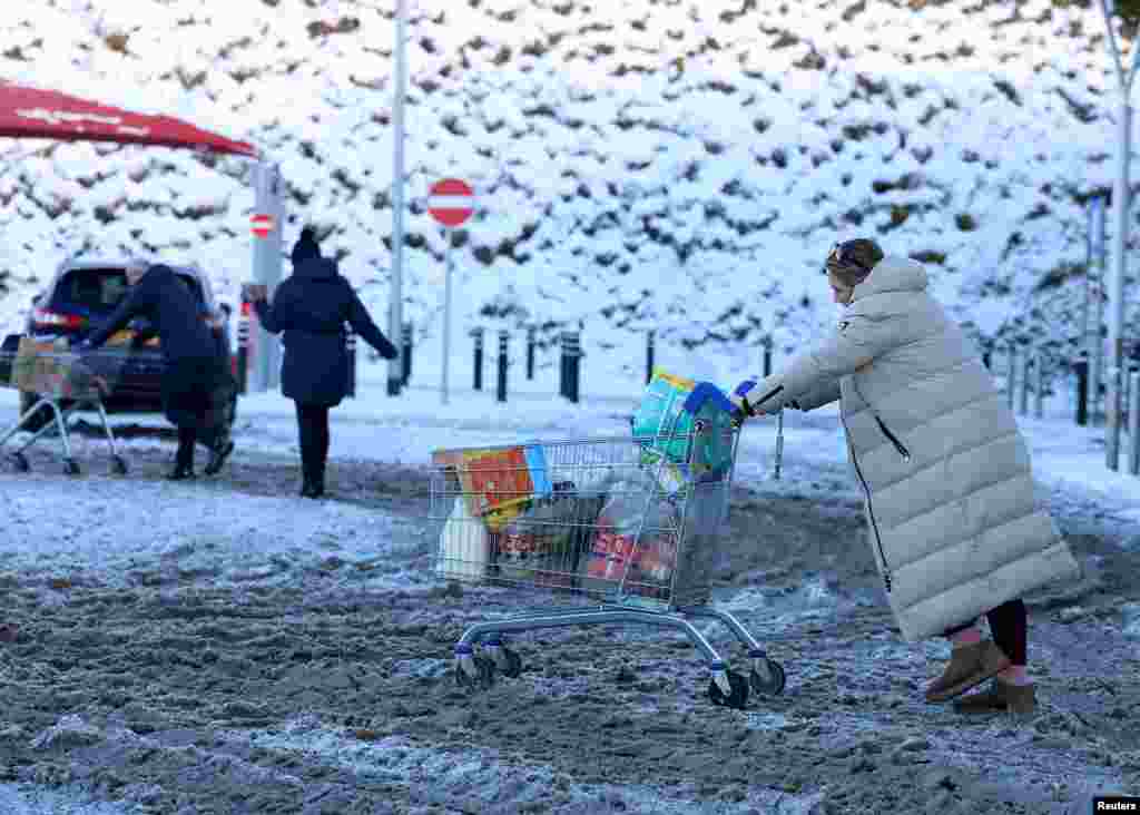 Žena gura kolica za kupovinu po snijegu, dok je britanska Meteorološka služba produžila upozorenja na veoma hladno i ledeno vrijeme u Ballymeni, Sjeverna Irska, 5. januara 2026.