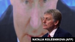 Дмитрий Песков на фоне видео-трансляции президента РФ Владимира Путина